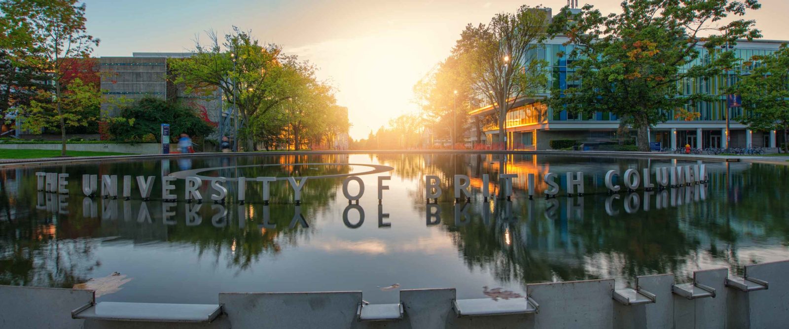 The University of British Columbia's reflecting pool at sunset, with the university's name in large letters along its edge.