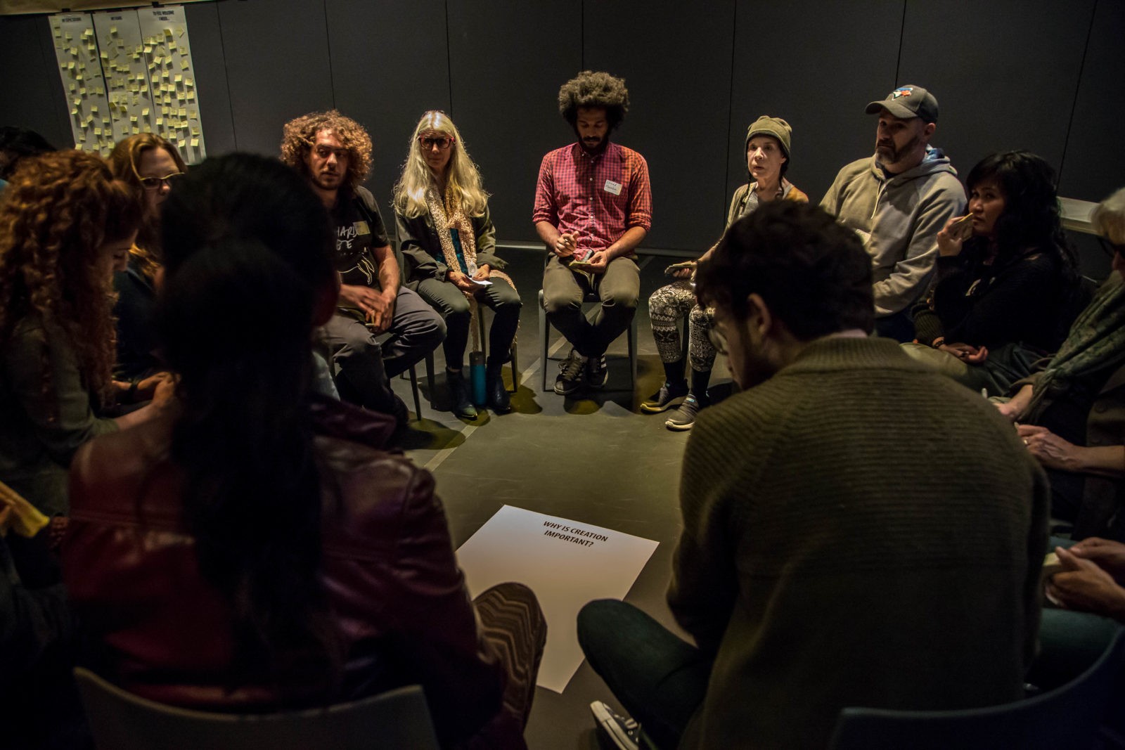 Participants seated in a close circle in a dark studio during a Postmarginal workshop at the Rutas Festival.