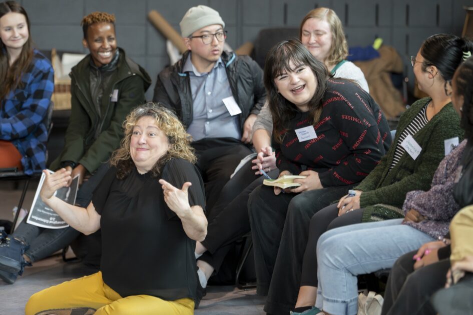 A group of people are laughing and smiling. They are gesturing with their hands.