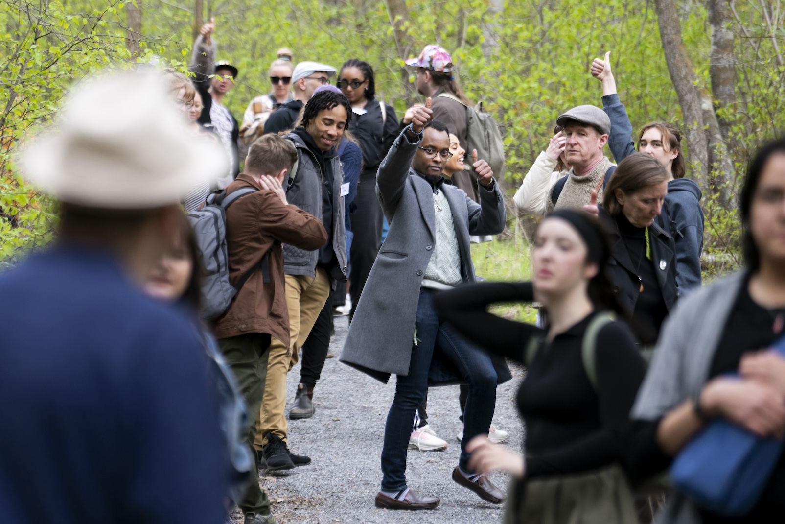 A group of people standing outdoors in a wooded area pump their hands in the air.