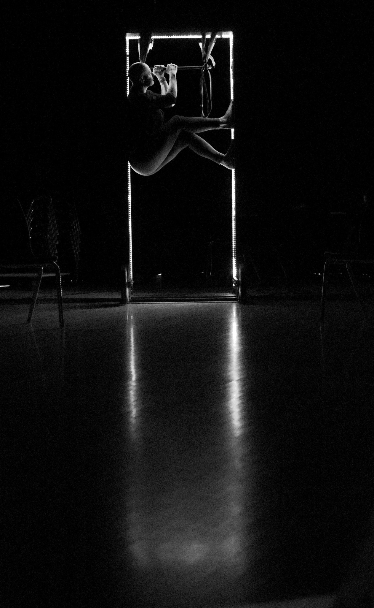 A woman is perched in.a door frame that is lit up from the inside.
