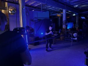 A man dances in an industrial space entirely lit in a blue light